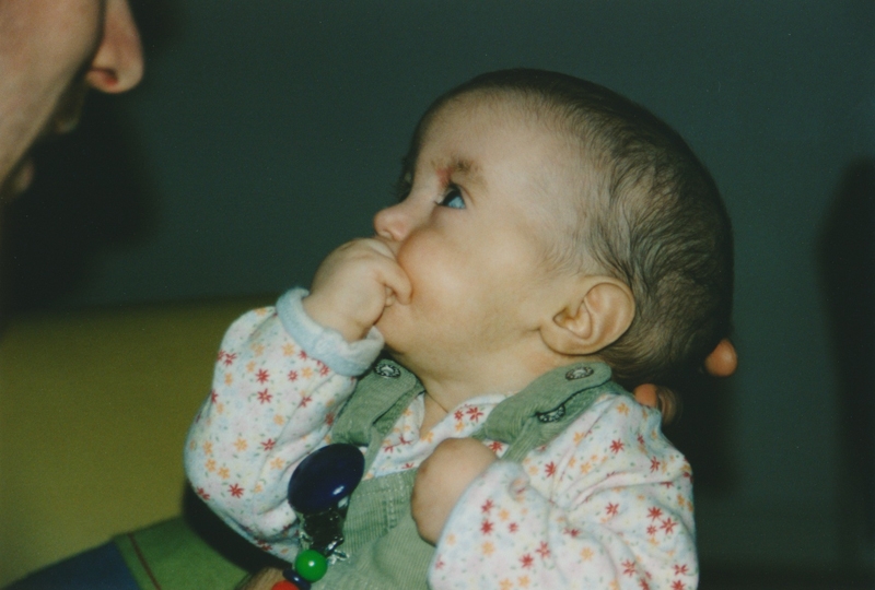Jaël (Trisomie 18) mit 6 Monaten, schaut ihren Papa an und hat die rechte Hand am Mund.