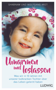 Buchcover mit dem Titel 'Umarmen und loslassen', zeigt ein lächelndes Kind mit einem bunten Hut. Untertitel beschreibt die Erfahrungen der Eltern mit ihrer todkranken Tochter.